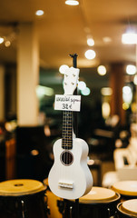 White Ukulele soprano guitar for sale in the windows of a music store in France