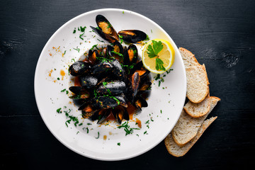 Mussels boiled in sauce. On a wooden background. Top view. Free space for your text.