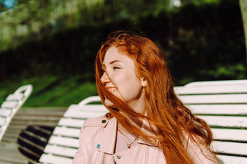 Attractive girl sitting on wooden bench in summer park