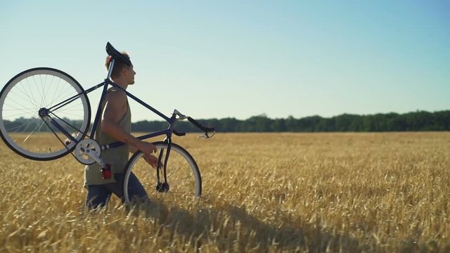Young boy walk with his bicycle at wheat field sundown slow motion rapid