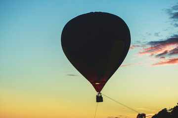 A flying aerostat hot air balloon in flight, with a sun dusk over the beach and blue sky 