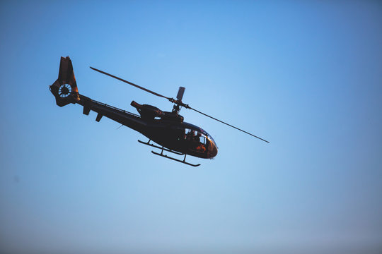 A flying black helicopter aircraft during the flight with blue sky in the background