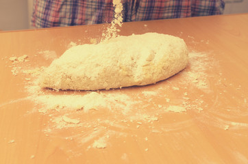 A woman kneads a homemade dough for pizza production.
