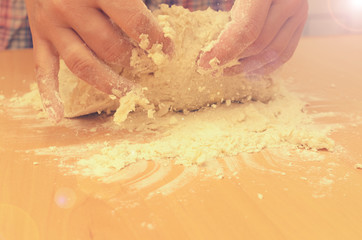 A woman kneads a homemade dough for pizza production.