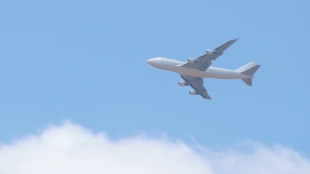 Close up of white cargo airplane passing on blue sky
