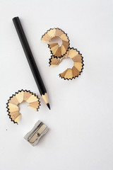 black coloured pencil, sharpener and pencil shavings