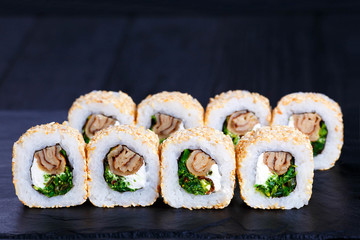 Delicious sushi rolls with chuka seaweed, omelet and cream cheese inside, served on black stone...