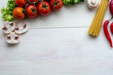 Pasta, tomatoes, salad, pepper and mushrooms on white wooden table background.