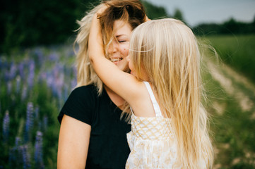 Young mother with long hair holding little daughter princess at hands. Playing with child. Pure,...