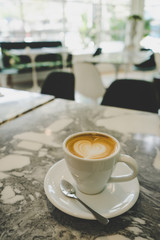 Cup of cappuccino on the marble table in the coffee shop.