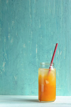 freshly-squeezed orange juice with ice on a pastel blue background.