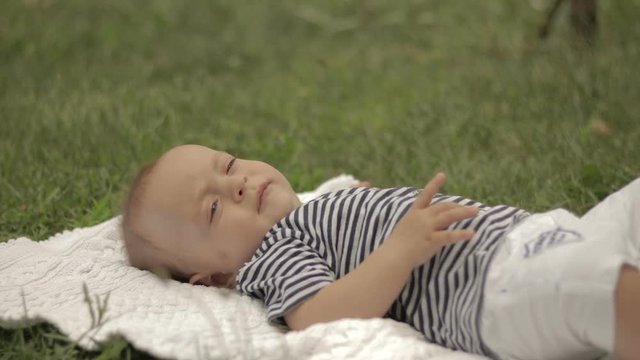 A small child lies on the grass grins and plays