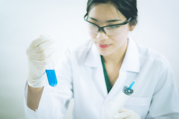 Young Asian scientist working in the lavatory with test tubes and other equipment to discover new drugs, products and methods of formulation
