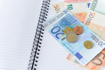 Money euro banknotes and coins on notebook