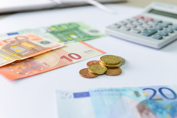 Euro money banknotes and coins counting with calculator on desk