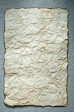 Vintage crumpled paper on grey surface vertical view