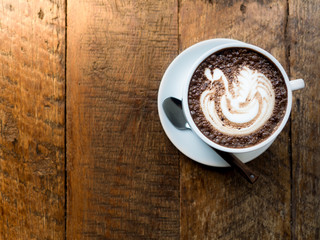 Top view of white coffee or hot milk chocolate cup on wood table, showing beautiful latte art at coffee shop in the morning of working day 