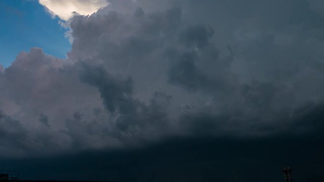 Massive huge dark clouds during the summer thunderstorm cover clean blue sky. Very rapid movement of clouds in the sky. Time lapse of dark sky during rain