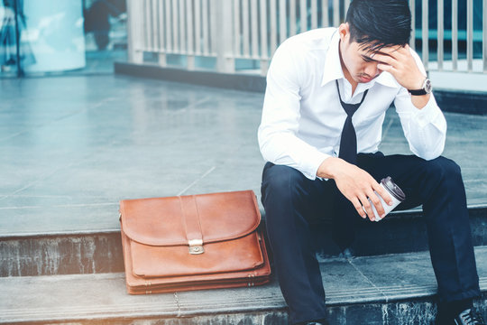 Tired or stressed businessman sitting on the walkway after work outdoor concept