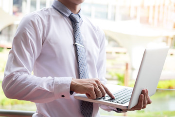 businessman using modern laptop for working at personal space outdoor,  wireless connection internet on his notebook computer