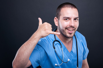 Doctor wearing scrubs with stethoscope making calling gesture