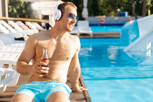 Smiling shirtless man relaxing near swimming pool