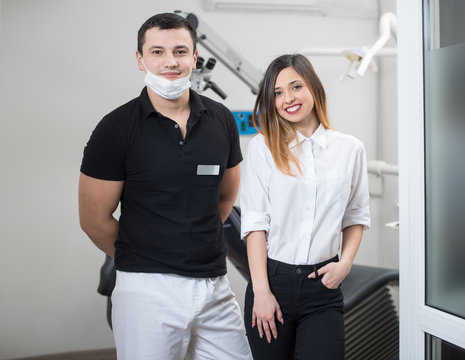 Portrait of handsome male dentist with smiling female patient after treatment in modern dental clinic. Dentistry