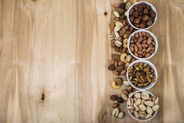 Four bowls with nuts on a  wooden table.