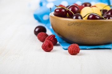 Ripe berries in a plate on a wooden table.