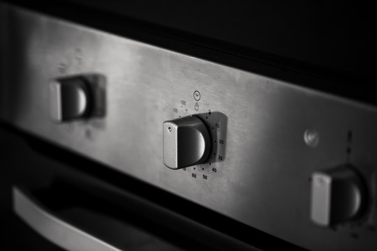closeup clean new kitchen gas stove cooker knob heat volume switch elegant metal steel black and white.
