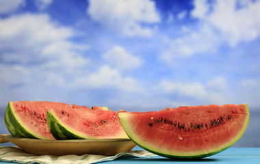 Watermelon slices on a wooden table - blue sky background