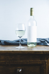 A glass of white wine and a bottle on old wooden table