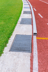 rain drainage in sport stadium - water drain hole around football field and running track.