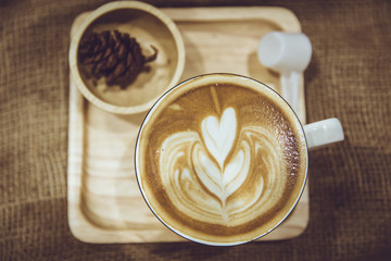 coffee latte art served on wood plate decorated in cafe brown color tone vintage style.