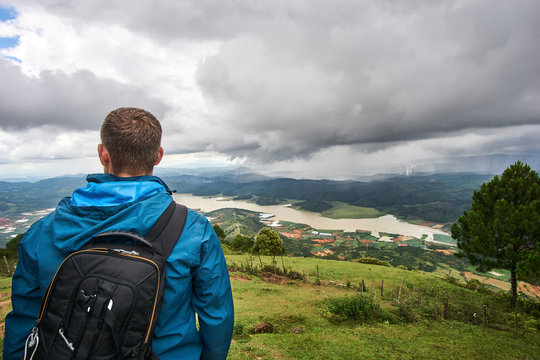 Young man standing on the mountain lang biang in Da-lat, Vietnam. Dramatic sky before the rain starts.