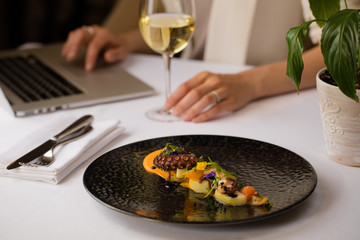 business lunch setting with seafood salad, wine and laptop