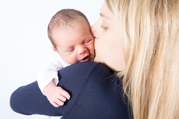 cute blonde mother with newborn baby kiss in arms