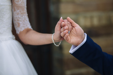 Closeup groom and bride are holding hands at wedding day ang show rings. Concept of love family
