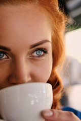 Portrait of redhead female barista drinks coffee.