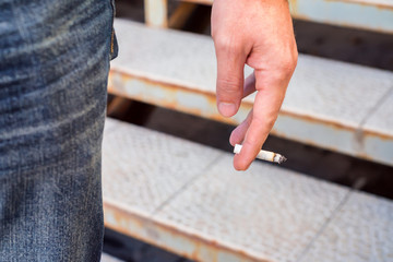 Male hand holds burning cigarette
