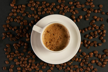 Coffee cup and coffee beans on a black stone table. Top view, time for coffee