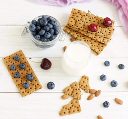 Breakfast for health glass of milk, blueberries and breads on white wooden background. top view