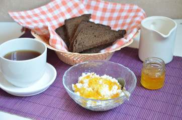 Breakfast on the table cup with tea milkwoman rye bread curds orange jam on a purple napkin