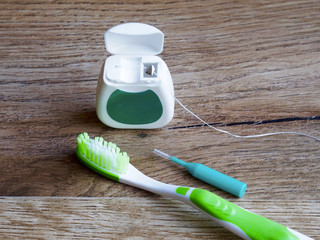 Dental floss, toothbrush and interdental brush on wood background
