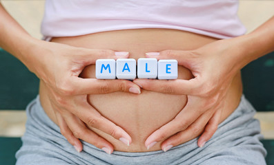 Woman holding character cubic "MALE" at her belly.