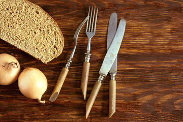 A slice of rye bread, onions and cutlery