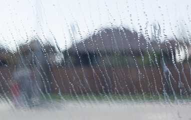 Natural water drop on glass outside the window, houses background.