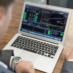 Corporate businessman analyzing economic data on laptop computer. Man's hands on notebook computer, business person at workplace.