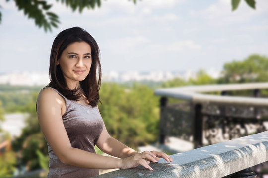 Portrait of happy smiling woman standing on the square on sunny summer or spring day outside, cute smiling woman looking at you, attractive young girl enjoying summer, flare sunshine