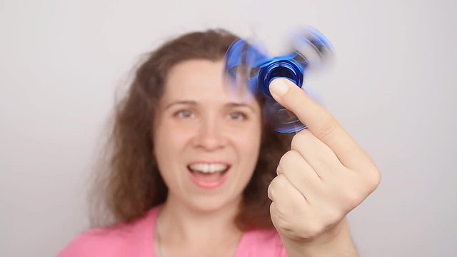 Young woman holding and playing with fidget spinner. studio shot on white background